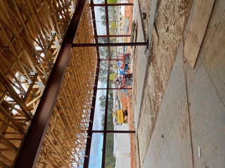 Steel beam and column frame supporting a wood-truss roof