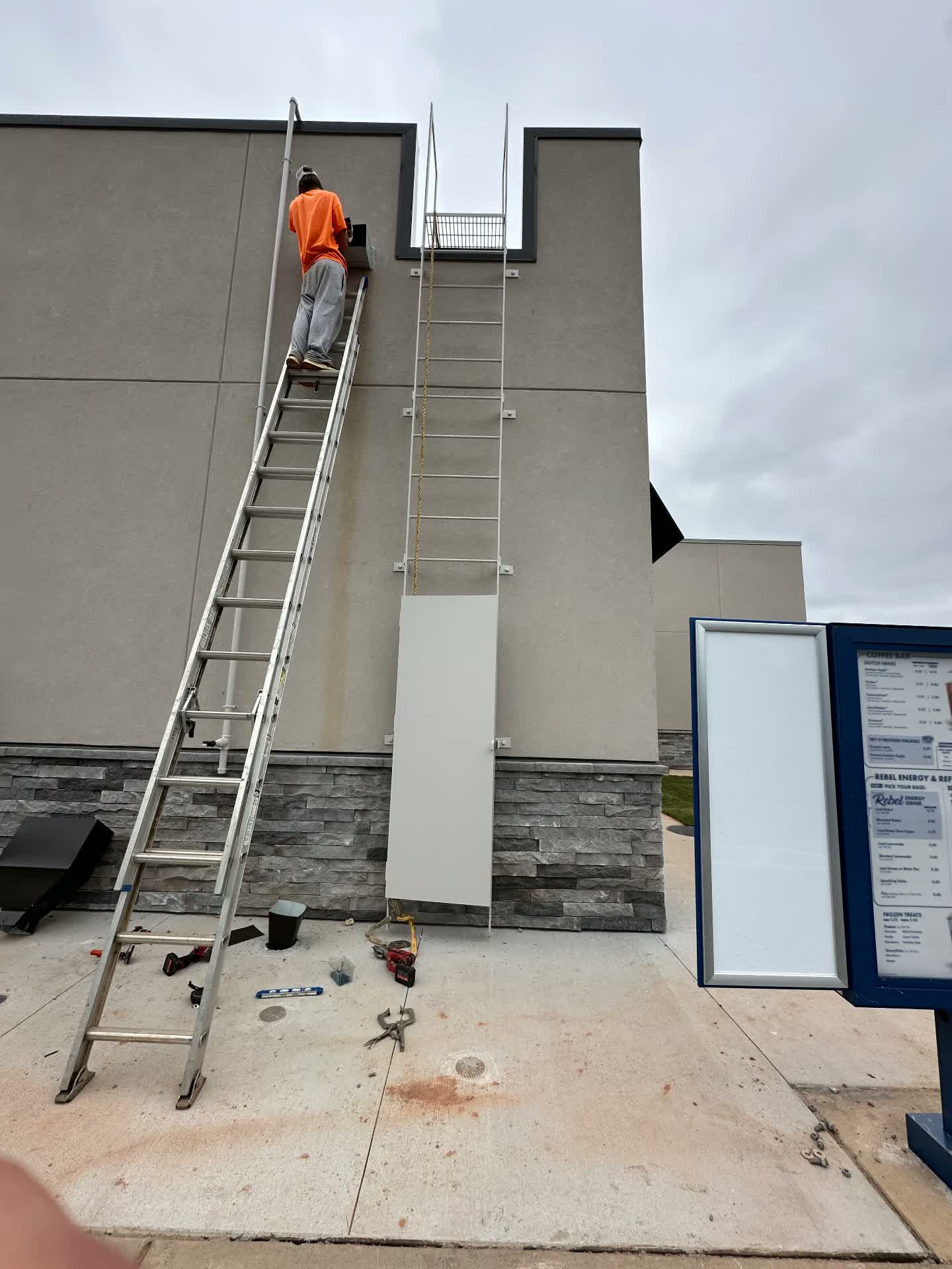 Crew installing a roof access ladder with safety cage