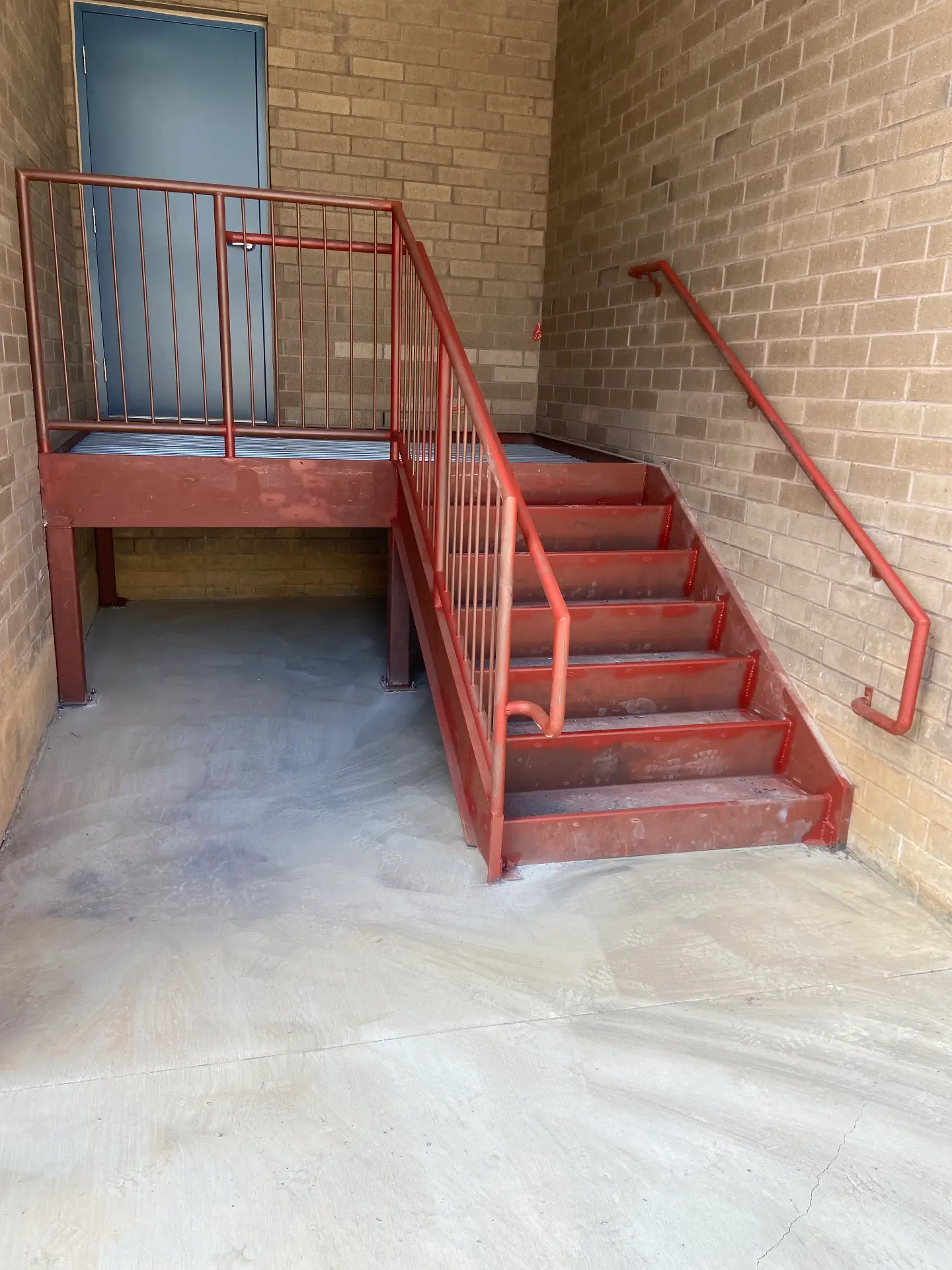 Red steel egress stair with landing and railing